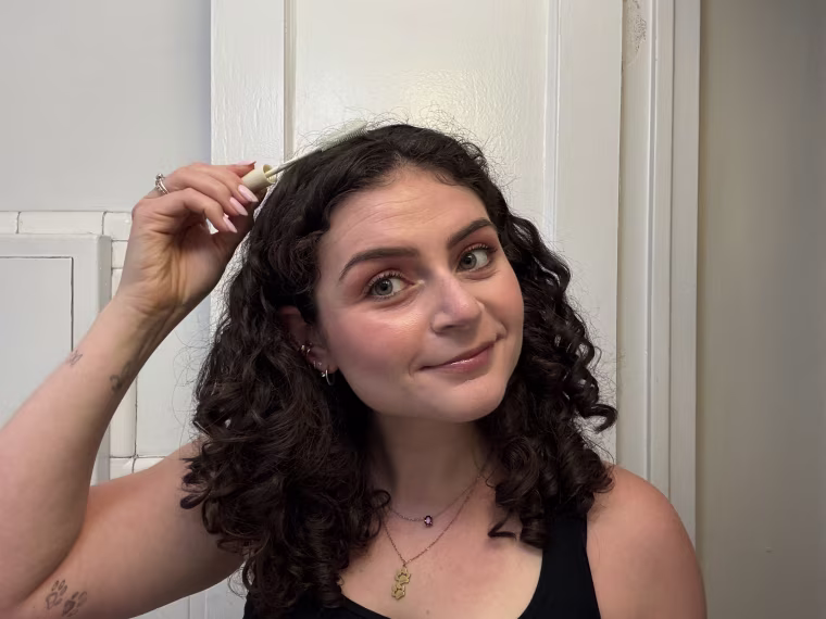 Woman applying taming wand to hair
