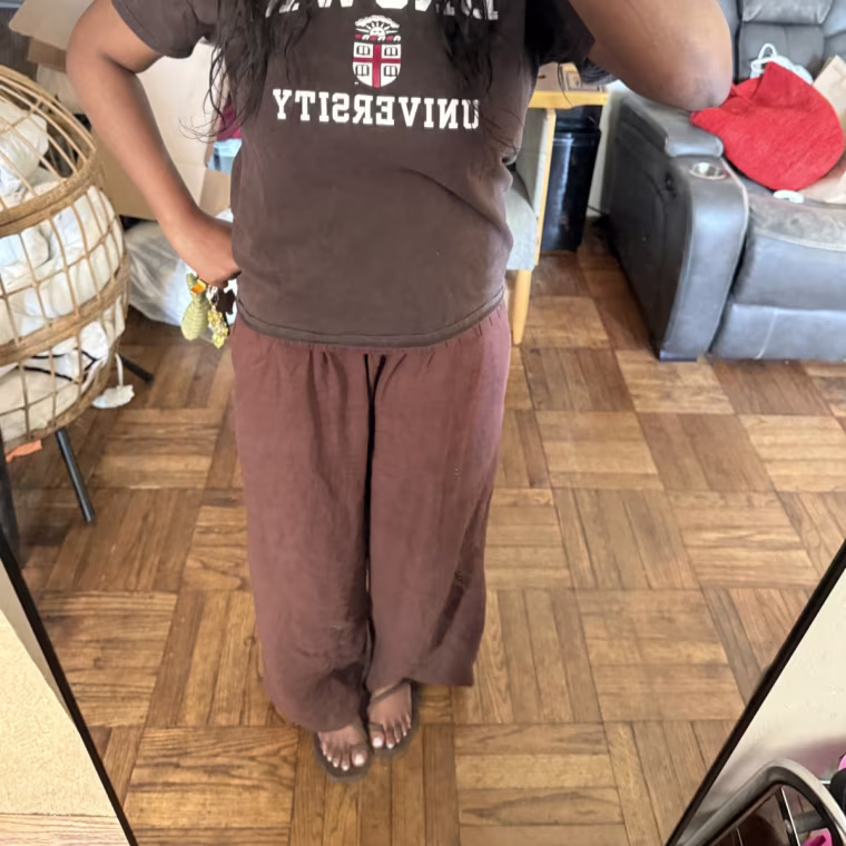 Alabi wearing the Crocs Miami sandals in her living room, with brown pants and a brown tee shirt, photographed in the mirror.