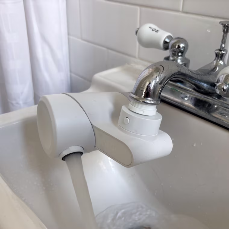 A white Qure Faucet Filter installed on a bathroom sink.