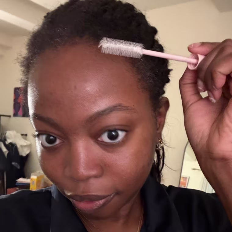 Woman applying taming wand edges of her hair