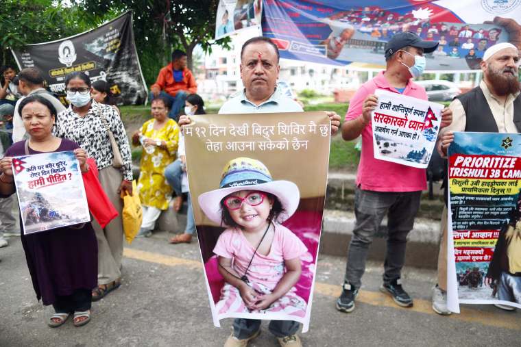 Family members of people missing in the flash floods hold photographs of their loved ones as they demand that the government expedite search and rescue efforts at hydropower stations at Maitighar Mandala.