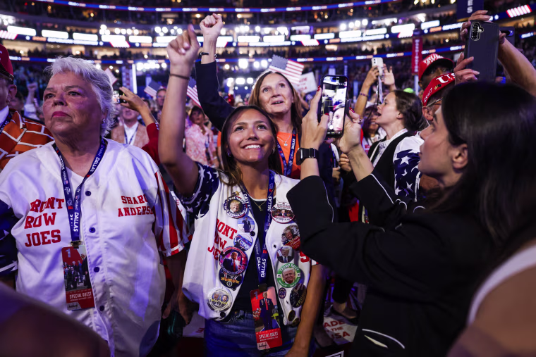 People listen as U.S. President Donald Trump speaks on stage.