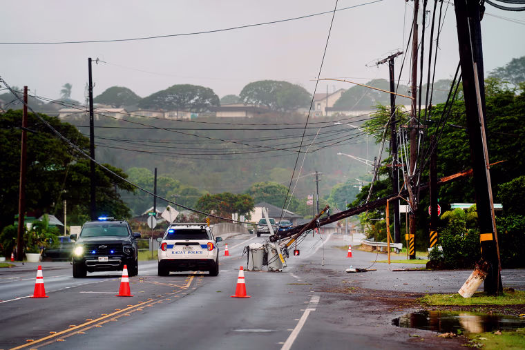 Downed power lines caused by Hurricane Lowell are seen across a road as police cars are parked