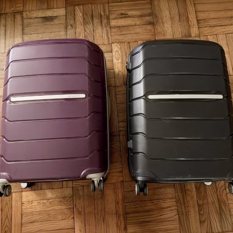A black and purple suitcase laying flat on a hardwood floor.