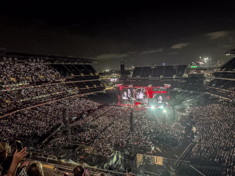 A wide shot of an outdoor stadium concert at night.