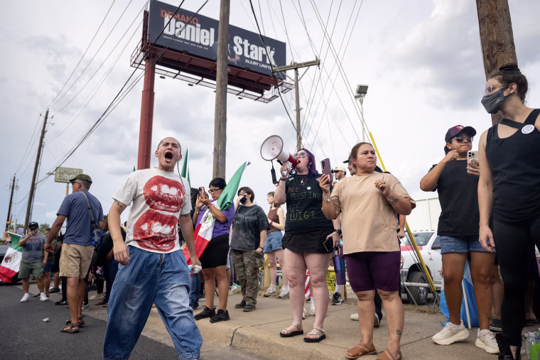 People gathered for a street protest alongside a roadway.