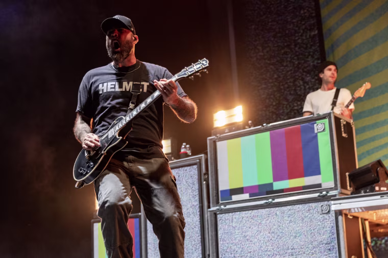 Chad Gilbert on stage in front of a speaker array during a live performance.