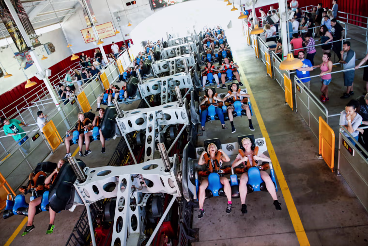 People are seated in the X2 roller coaster before it runs