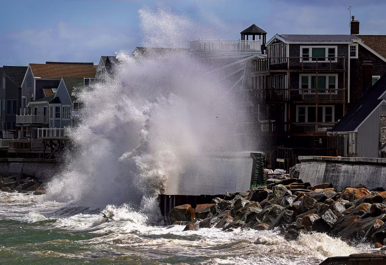 A wave crashes over an unfinished seawall.
