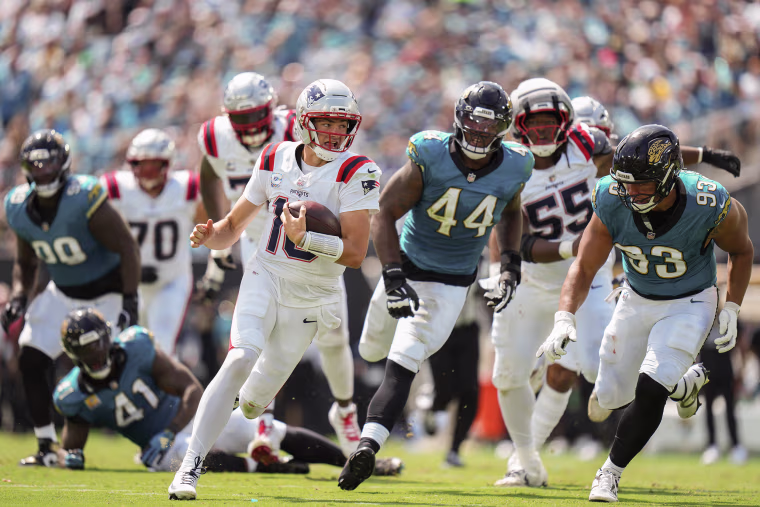 Drake Maye running the football in front of several Jaguar defenders. 