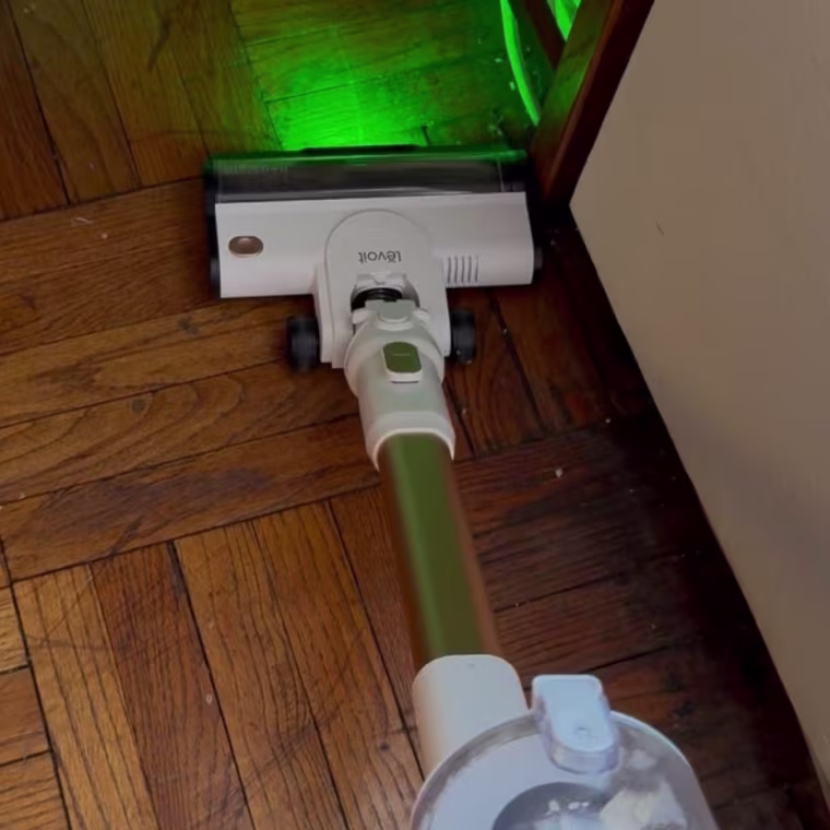 Photo of a vacuum cleaner emitting a green light on a hardwood floor
