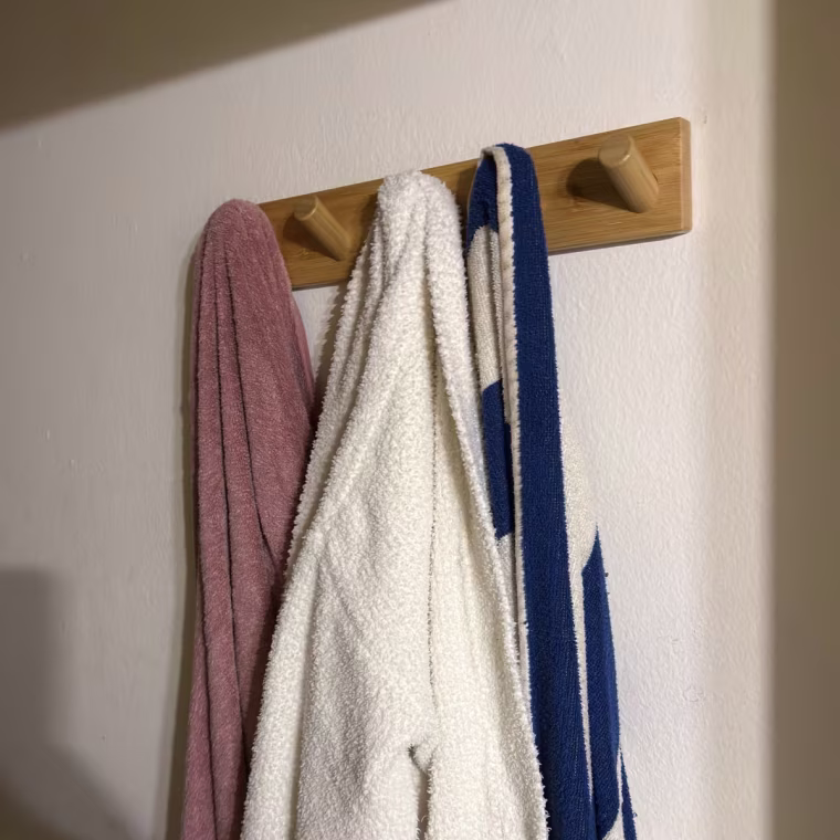 Photo of a wooden rack with multiple towels hanging on it.