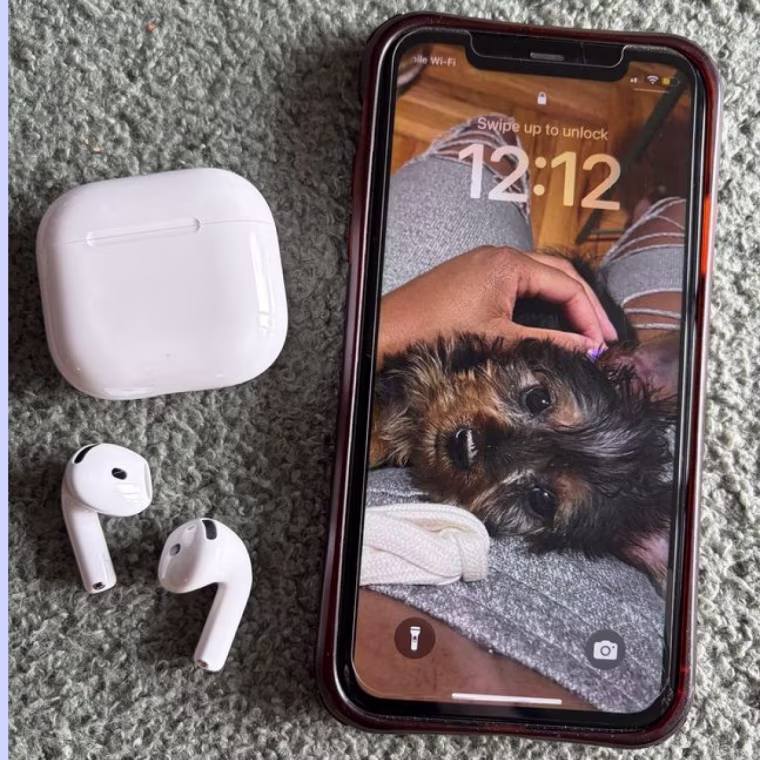 Apple AirPods 5 on a table near an iPhone.