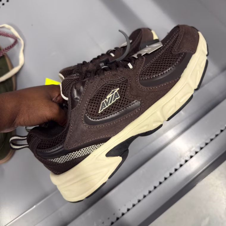 Photo of a hand holding brown sneakers.