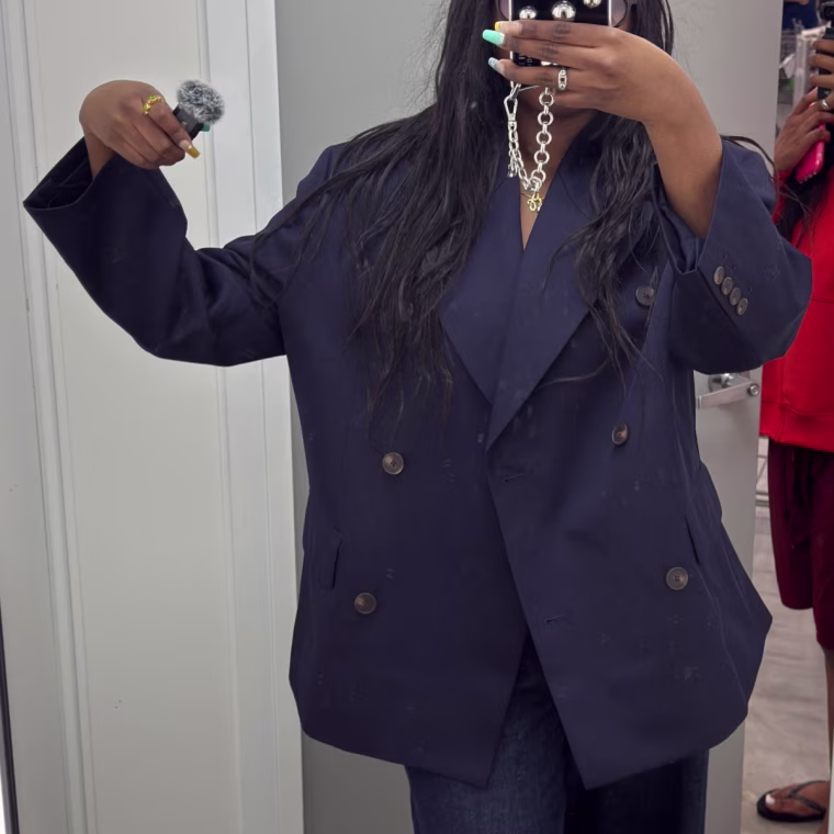 Mirror selfie of a girl in a dressing room wearing an oversized navy blue blazer.