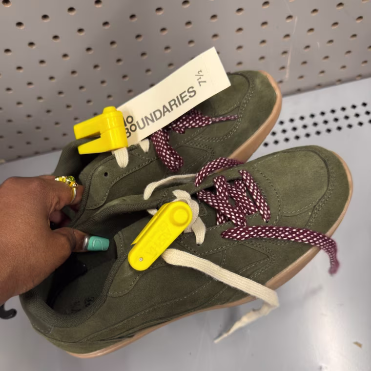Photo of a hand holding green sneakers.