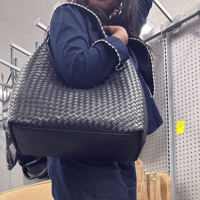 Photo of a girl holding a black woven handbag.