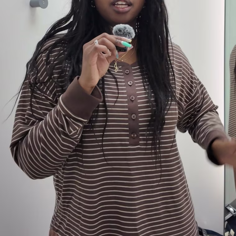 Photo of a girl wearing a striped long sleeve top while holding a small mic.