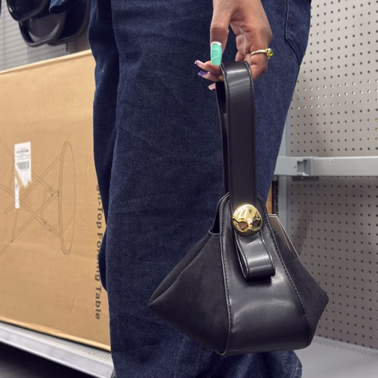 Photo of a person’s side holding a small black purse.