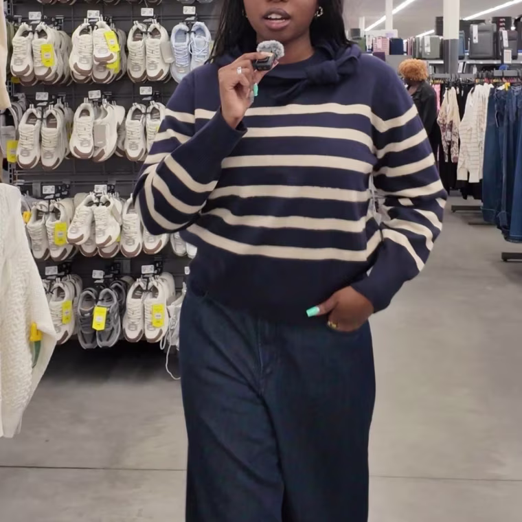 Screen grab of a girl wearing a striped sweater with jeans while walking through a department store. 