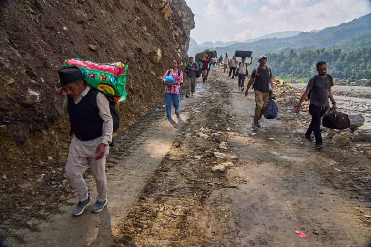 People walk on a road washed out by the floods in Nuwakot, Nepal, Friday, Oct. 2, 2026. 