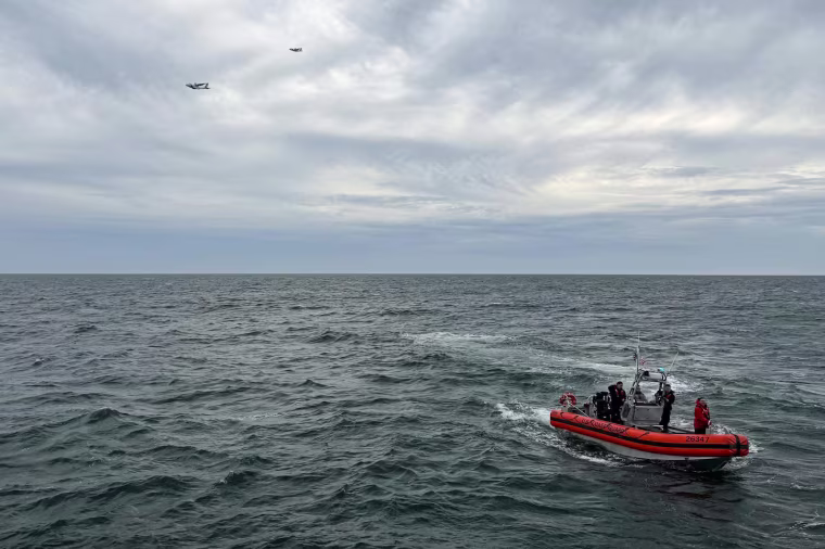 A coast guard boat with four people on it in the ocean