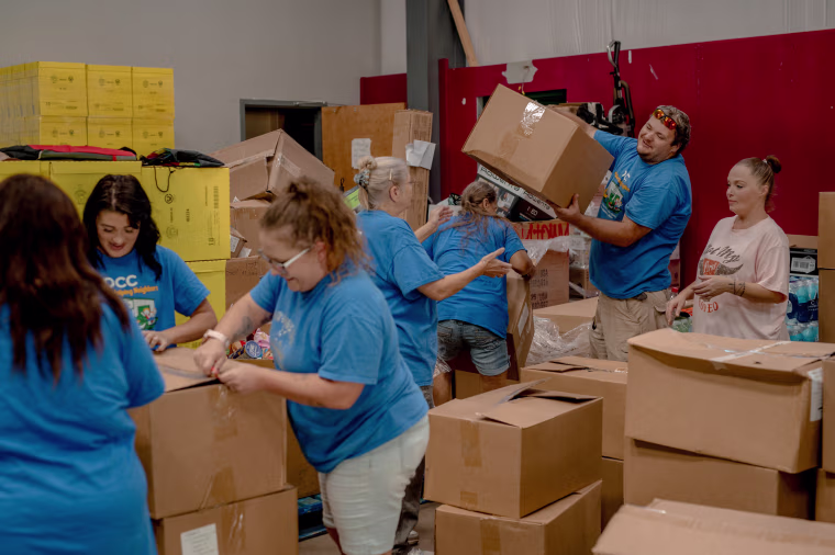 Volunteers and staff members sort through a maze of boxes of donated goods inside the Dunlow Community Center.