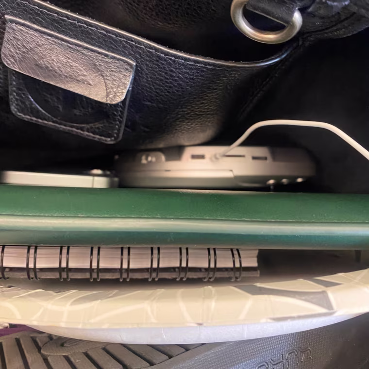An aerial view of the Lola CD player in a bag with notebooks, a laptop and other work accessories.