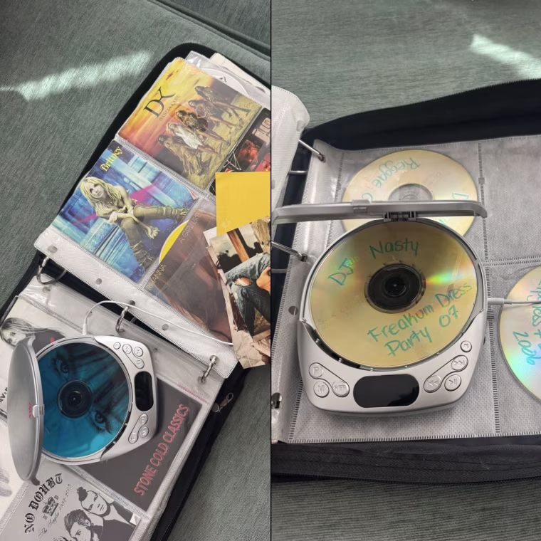 The Lola CD player on top of a book of CDs with the top open and a CD inside.