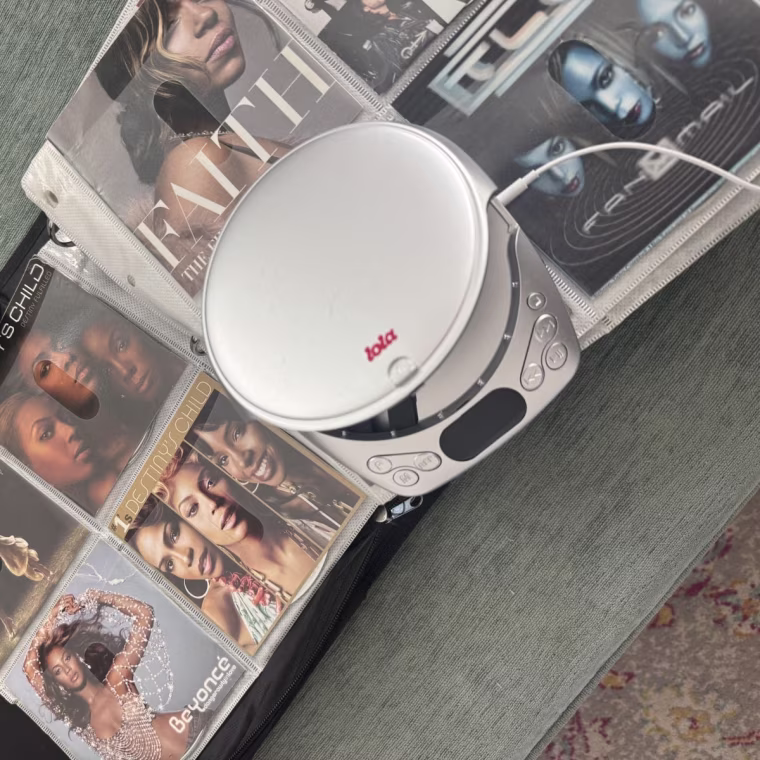 The Lola CD player on top of an open book of CDs and CD covers.