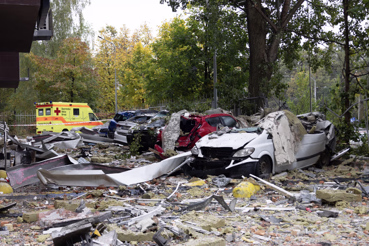 Image: Destroyed cars among debris in a residential building courtyard.