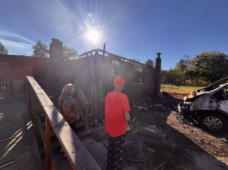 From left, Larita and James stand in front of their charred home
