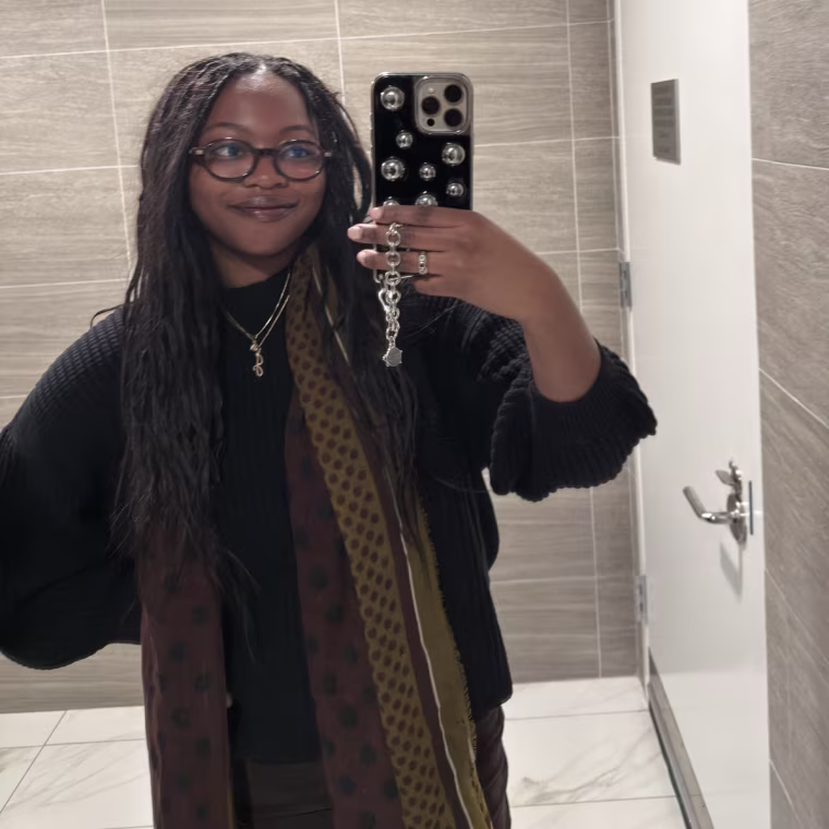 Mirror selfie of woman wearing a black waffle sweater with a scarf.