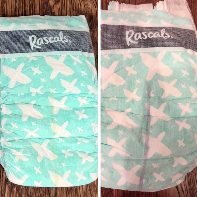 Side-by-side photos of a teal Rascals diaper with a white X print, showing a yellow wetness line on the left and a dark purple line on the right.