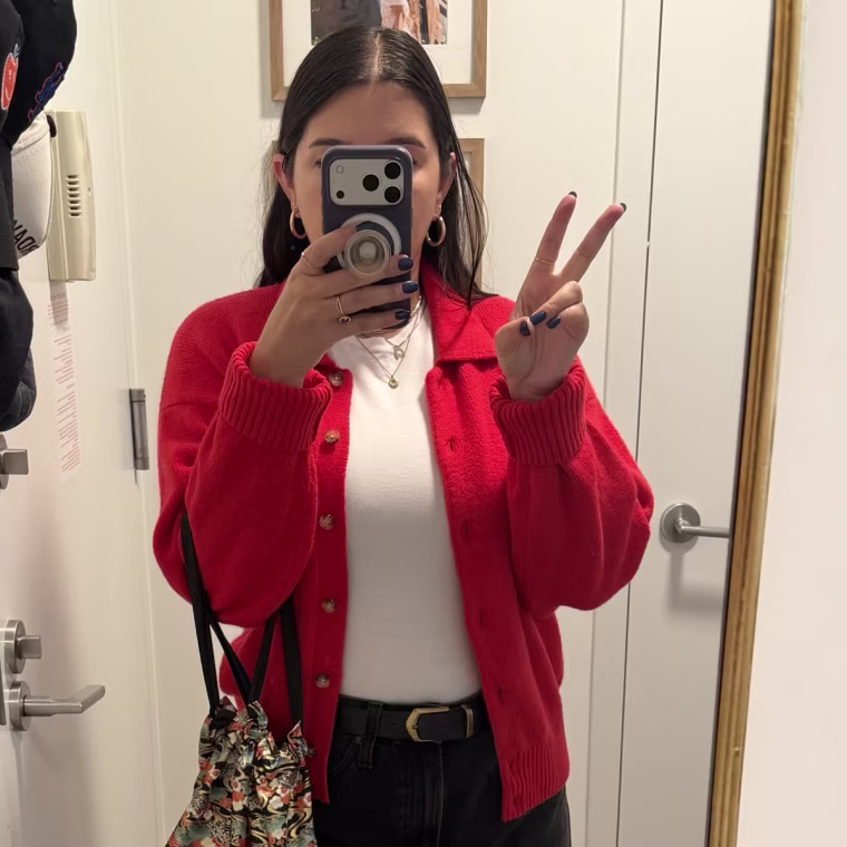 Person wearing a red cardigan in a mirror selfie.