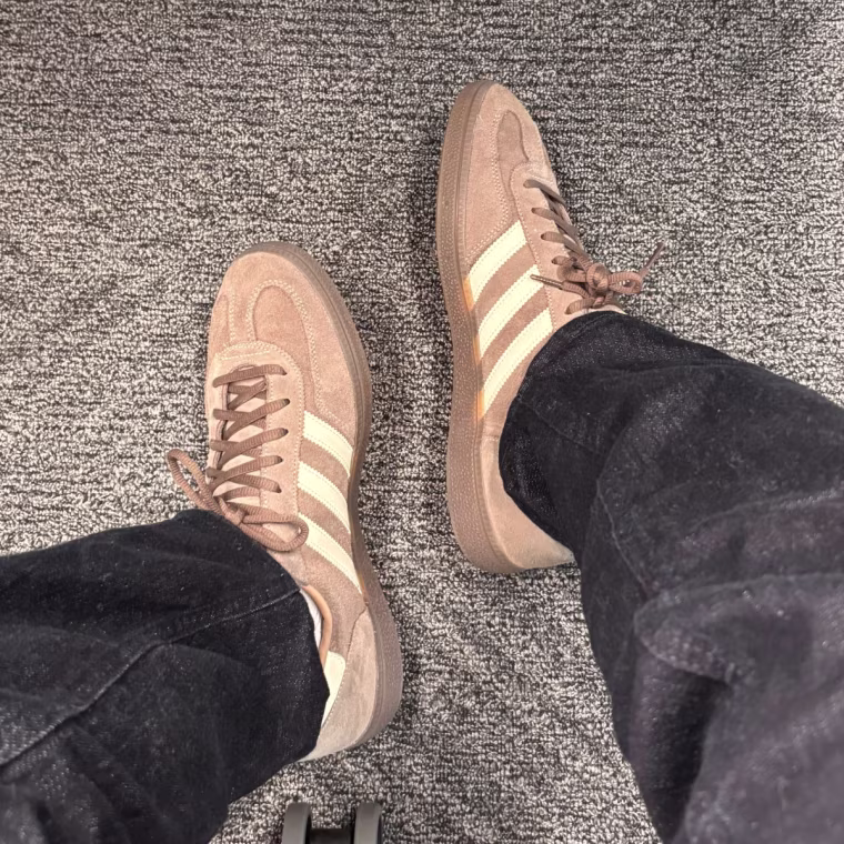 Person wearing brown Adidas Handball Spezial Shoes in a chair.