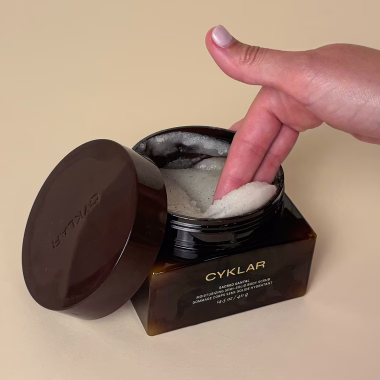 Woman scooping out body scrub from tub