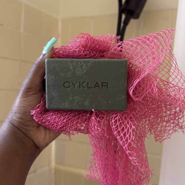 Woman holding green Cyklar bar soap in bathroom shower