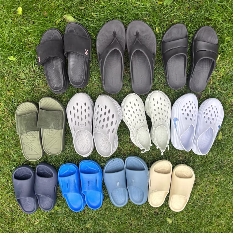 10 pairs of recovery shoes grouped together on grass.
