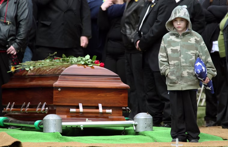 Nicholas Weichel, son of Sgt. Dennis Weichel Jr., stands next to his father's casket during funeral services.