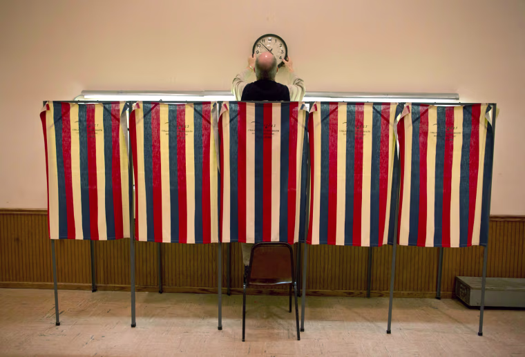 An election worker puts up a clock above voting booths in Saukville, Wisconsin, on April 3. Reports state that voters are going to the polls in Wisconsin, Maryland and Washington to make their choice in the Republican presidential primary election.