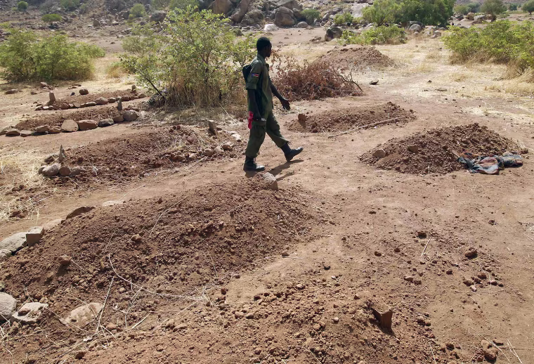 A SPLA-N soldier walks next to fresh graves of Nuba people killed during raids by Sudan's air force in the Nuba Mountains, South Kordofan, Sudan.