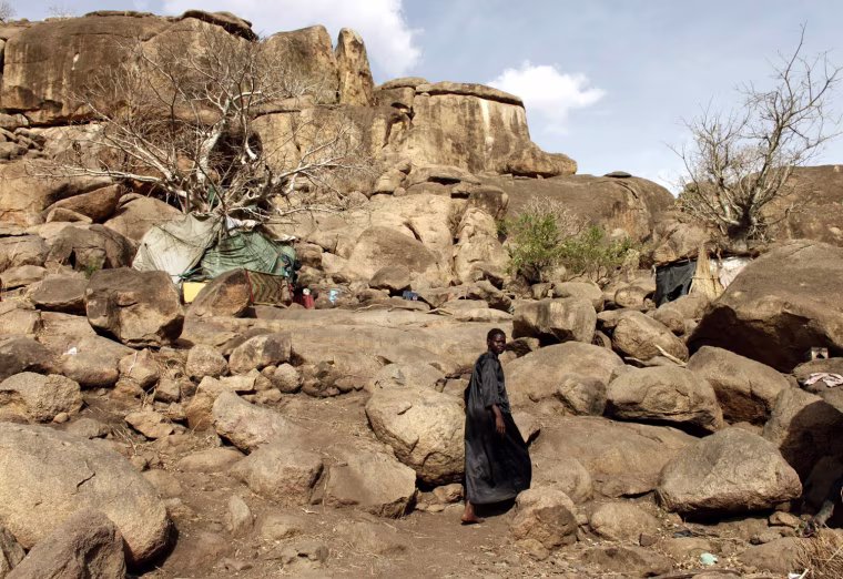 A woman walks towards a cave shelter in Bram village in the Nuba Mountains in South Kordofan.