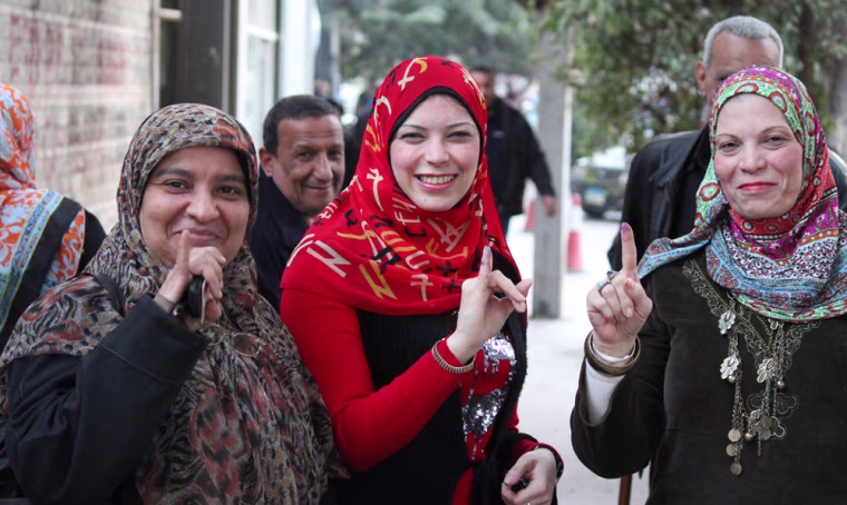 Um Aziza and her daughter Nuha Yemeni, center, show that they voted Saturday.