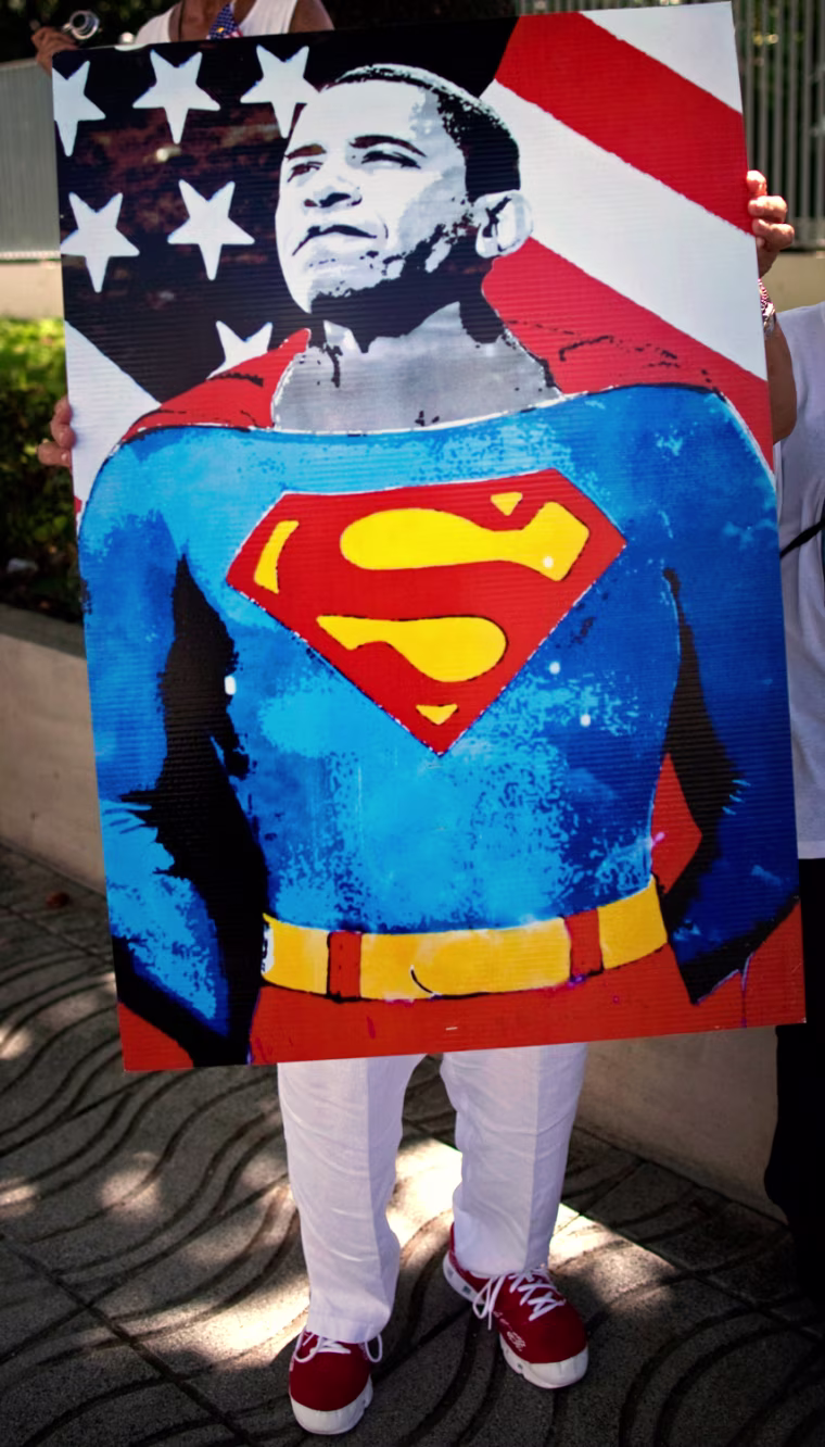 A woman holds an image of President Barack Obama, dressed as comic book superhero Superman, as she waits for the presidential motorcade in San Juan, Puerto Rico, Tuesday, June 14, 2011. Obama's one-day trip to the island marks the first visit to Puerto Rico by a sitting U.S. President since John F. Kennedy's 1961 visit. (AP Photo/Ramon Espinosa)