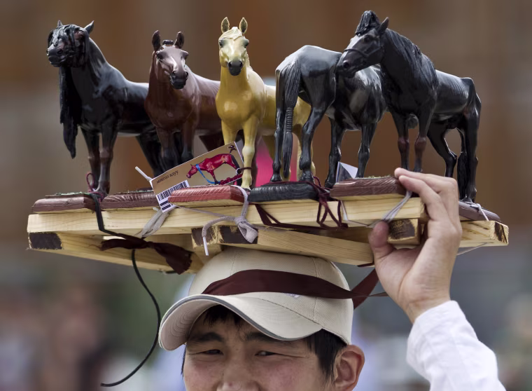 A Mongolian vendor displays figure horses for sale during the Naadam Festival in Ulan Bator, Mongolia, Wednesday, on July 11. Mongolians celebrate the anniversary of Genghis Khan's march to world conquest on July 11 with the annual sports festival featuring traditional Mongolian events including wrestling, archery, and horse racing.