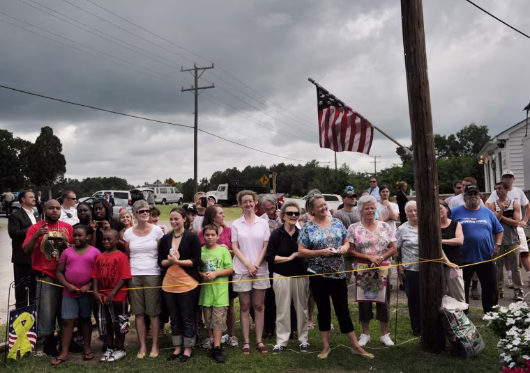 Under an overcast sky, onlookers watch as US President Barack Obama stops at Berry's Produce on July 14, in Mechanicsville, Virginia. Obama is campaigning in Virginia for the second straight day ahead of the November presidential election.