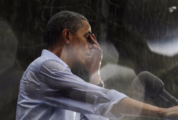 U.S. President Barack Obama wipes water off his face during a rain shower at a campaign rally in Glen Allen, Virginia, July 14.
