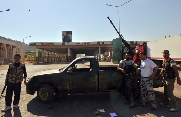 Syrian rebels stand next to their vehicle after seizing control of the Bab al-Hawa border post with Turkey on July 20, 2012. Some 150 armed rebel fighters were in control of the post, which lies opposite Turkey's Cilvegozu border crossing in the southern province of Hatay.