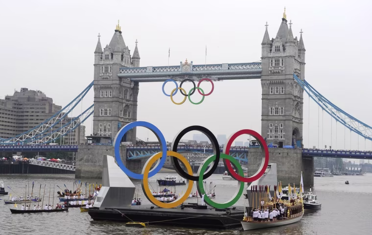 Olympic torch bearer Amber Charles holds the Olympic flame on a floating pontoon in front of Tower Bridge in London on July 27, 2012.